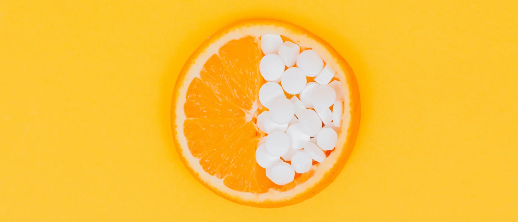 Orange half filled with supplement pills