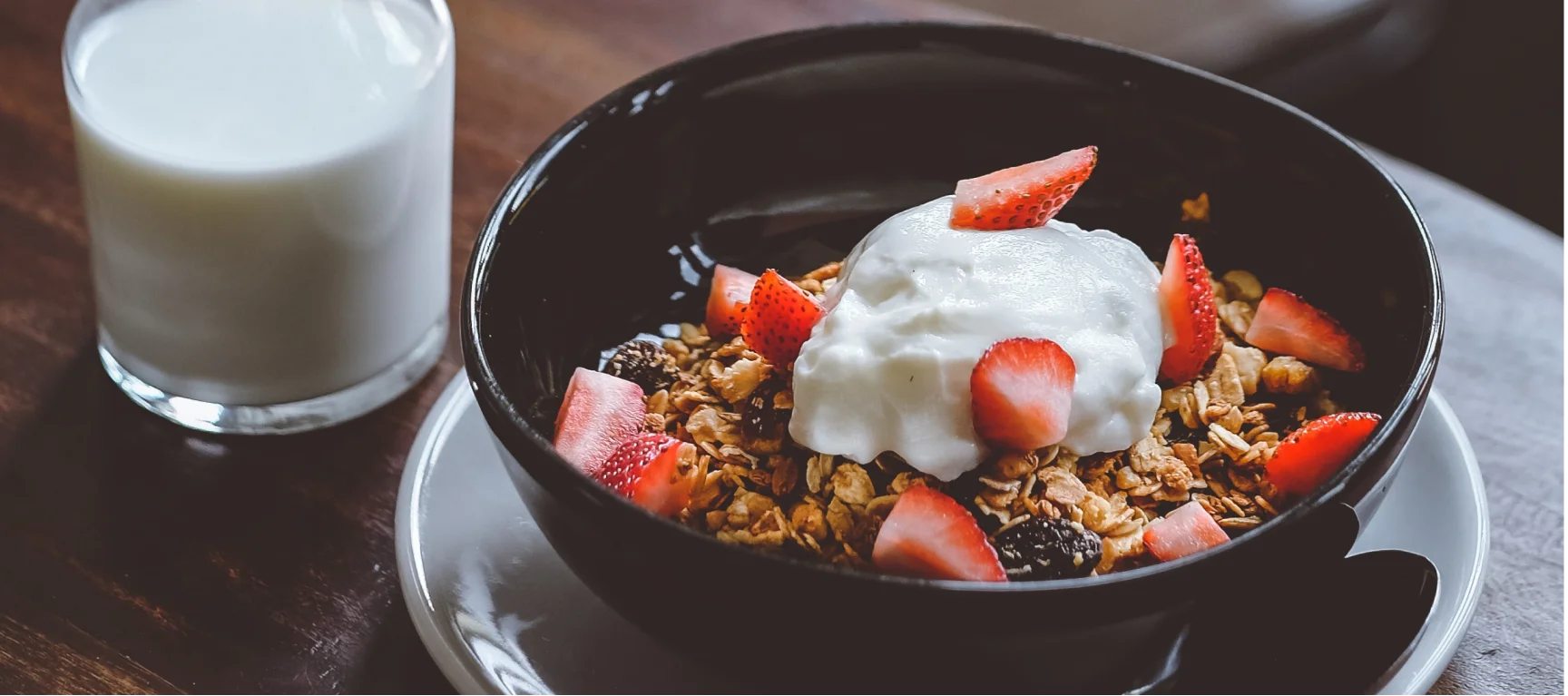 Muesli bowl with strawberries, quark and a glass of milk