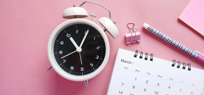 Clock and blocknote on pink table