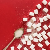 Spoon with sugar surrounded by sugar cubes