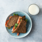 Sandwich with diary spread, salmon fillet and a glass of milk