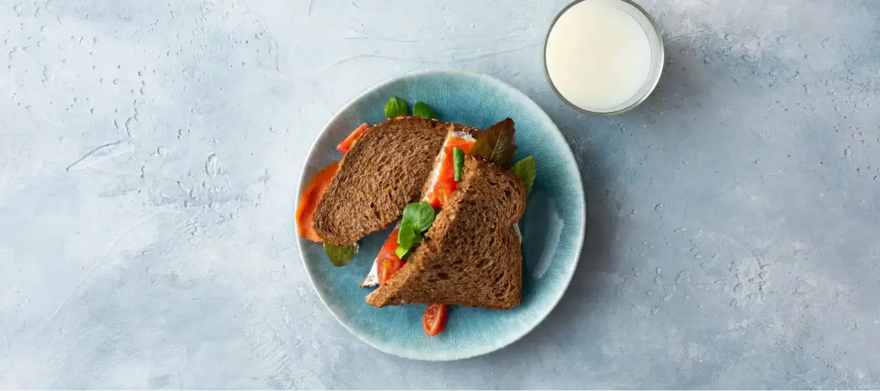 Sandwich with dairy spread, salmon fillet and a glass of milk